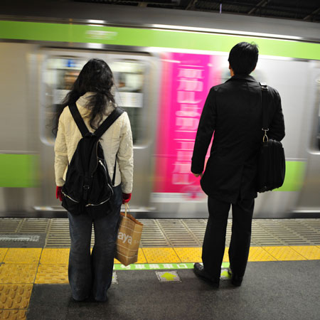 Two people stand in front of a subway train